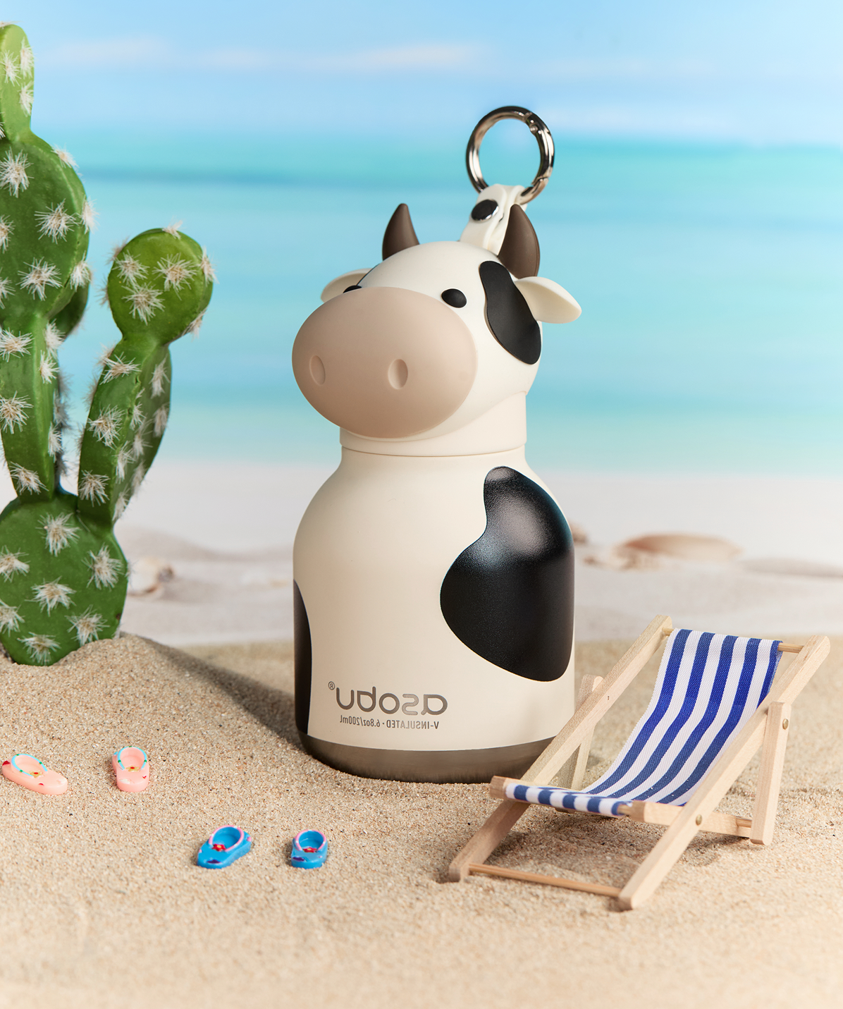 Botella mini térmica Asobu Bestie Vaca en un entorno de playa, ideal para hidratación rápida.