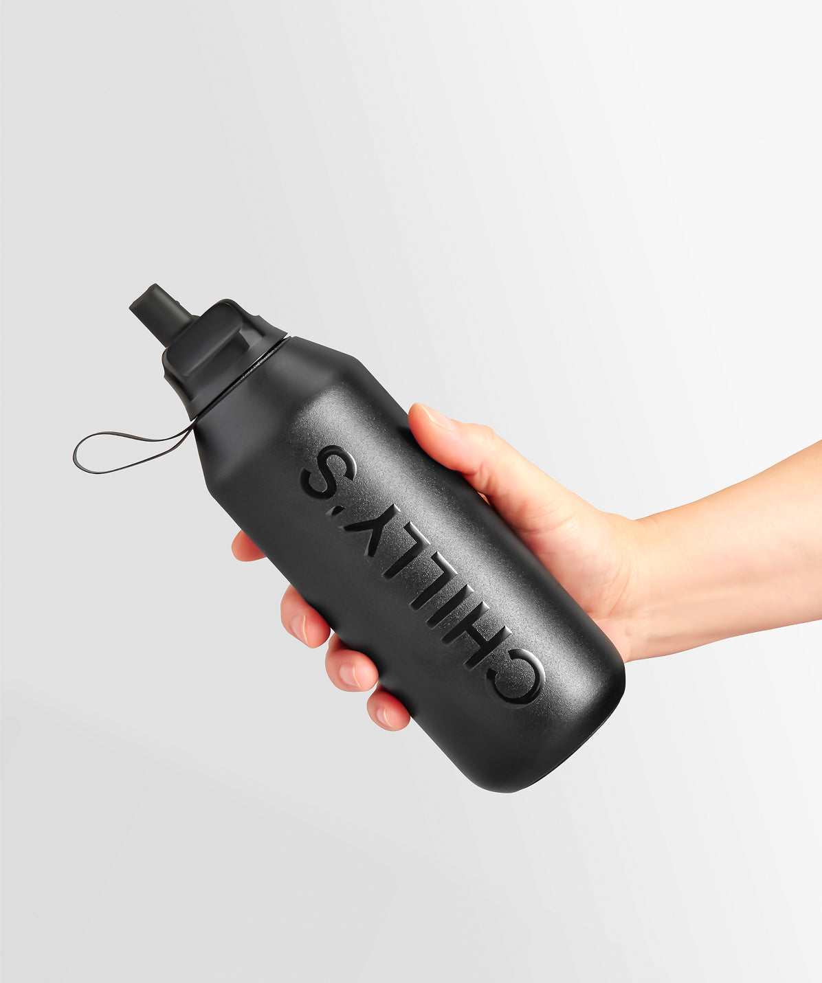 Botella Chilly's negra de 500ml sostenida en la mano, mostrando su tamaño compacto para el transporte diario.