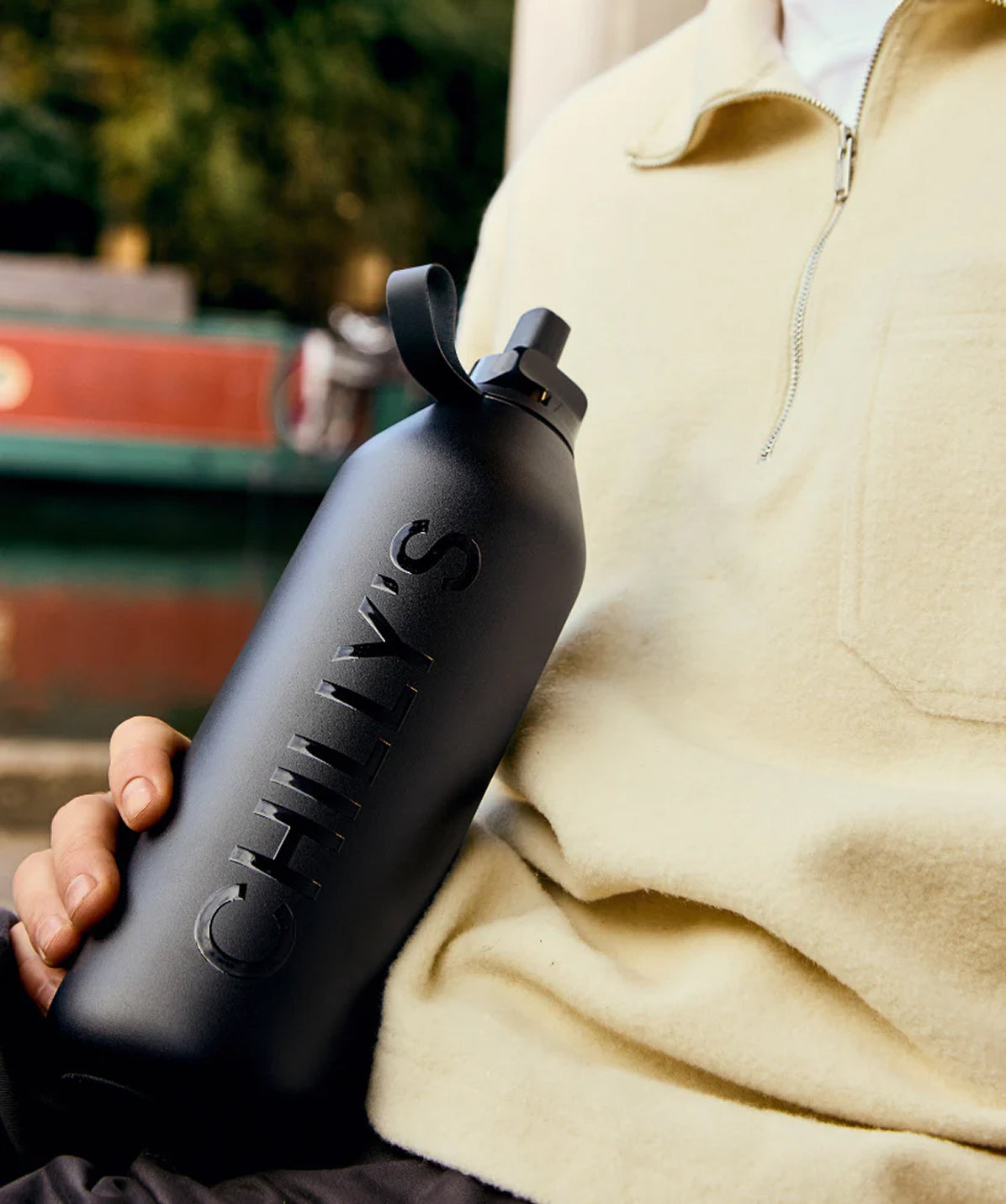 Botella Chilly's negra de 500ml sostenida en la mano, mostrando su tamaño compacto para el transporte diario.