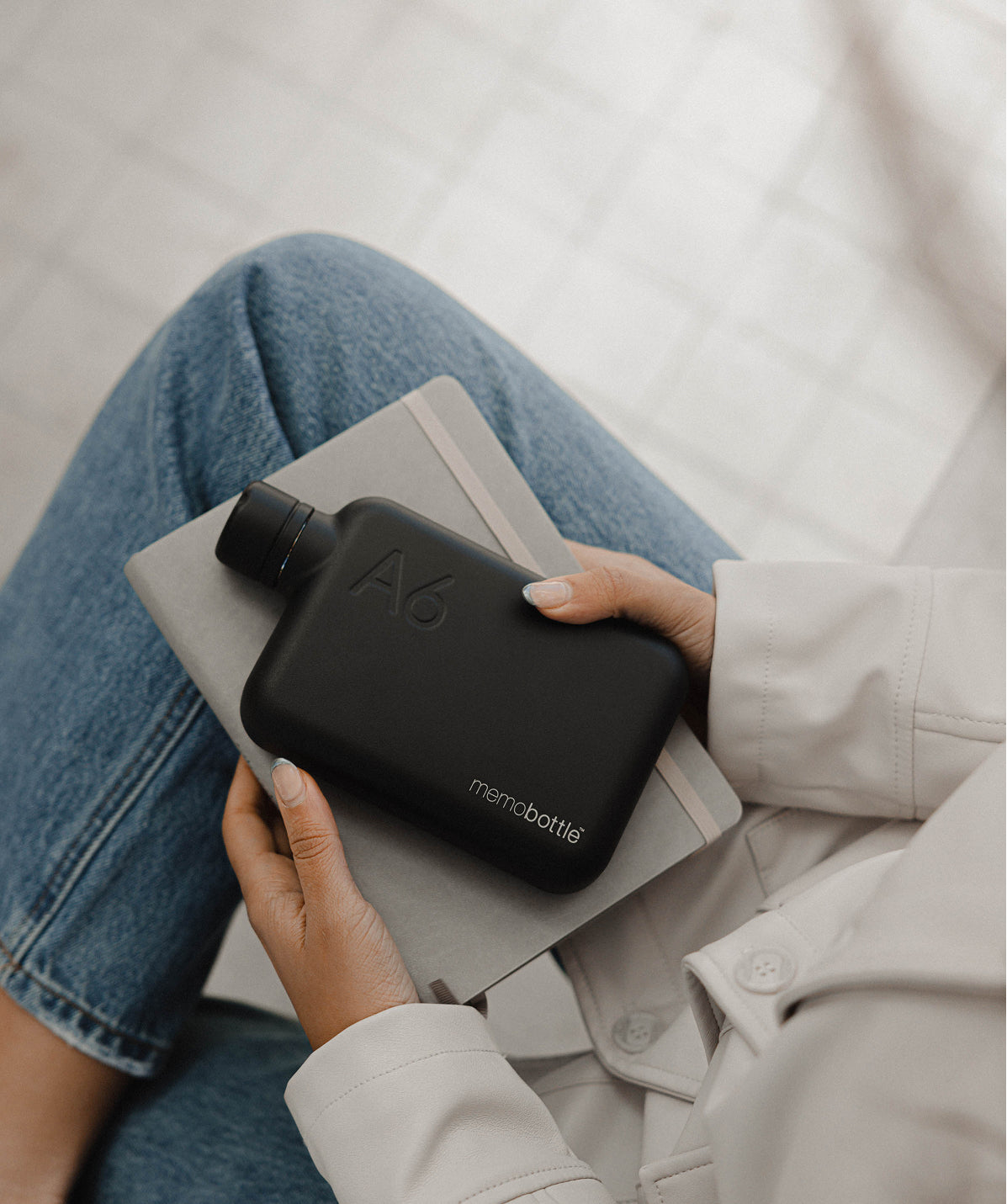 Memobottle A6 plana negra de acero inoxidable (500ml), sostenida en la mano, diseñada para llevar en cualquier bolso o mochila.