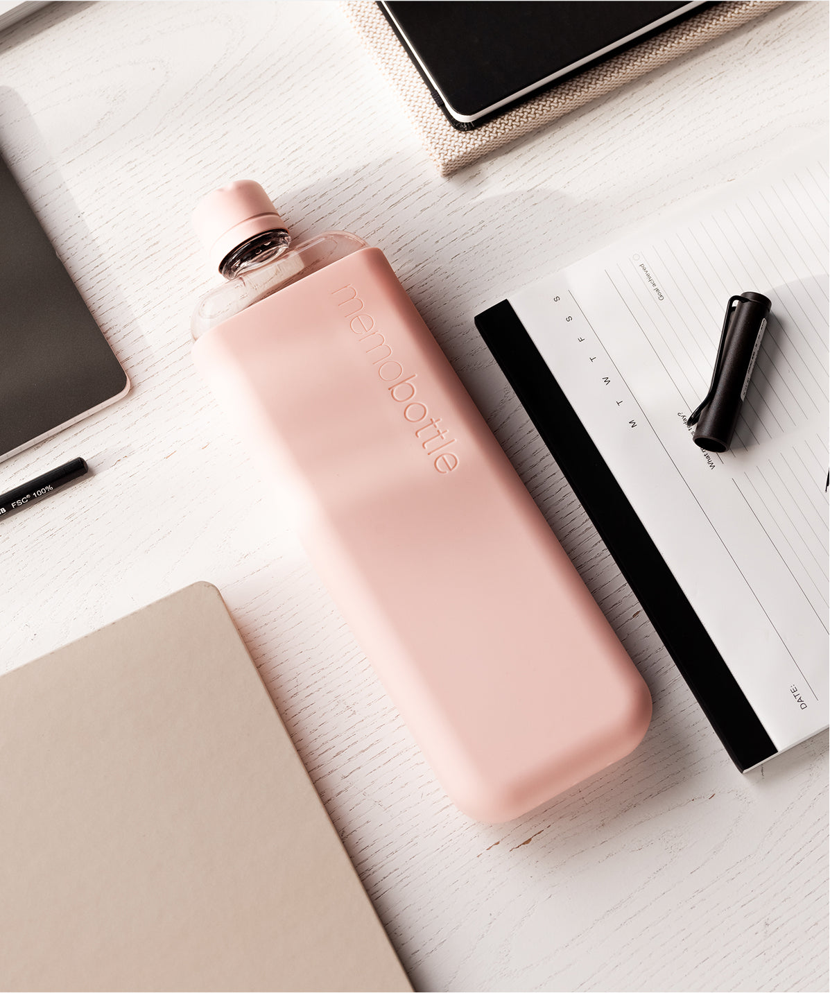 Botella Memobottle Slim rosa (450ml) con funda, diseño plano para ahorrar espacio en el escritorio o mochila de trabajo.