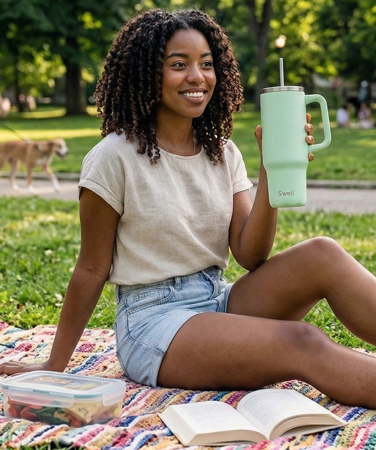 Chica bebiendo del vaso S'well Tumbler XL Pistachio verde pastel en un parque.