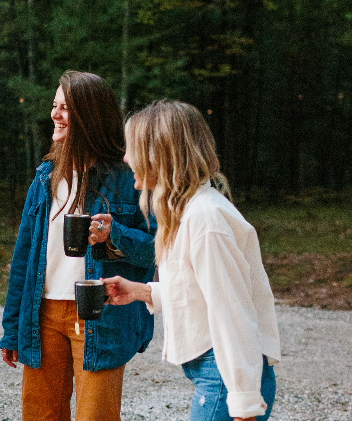 Mujeres compartiendo un café con la taza térmica S'well Mug Stone Onyx negra en la mano.