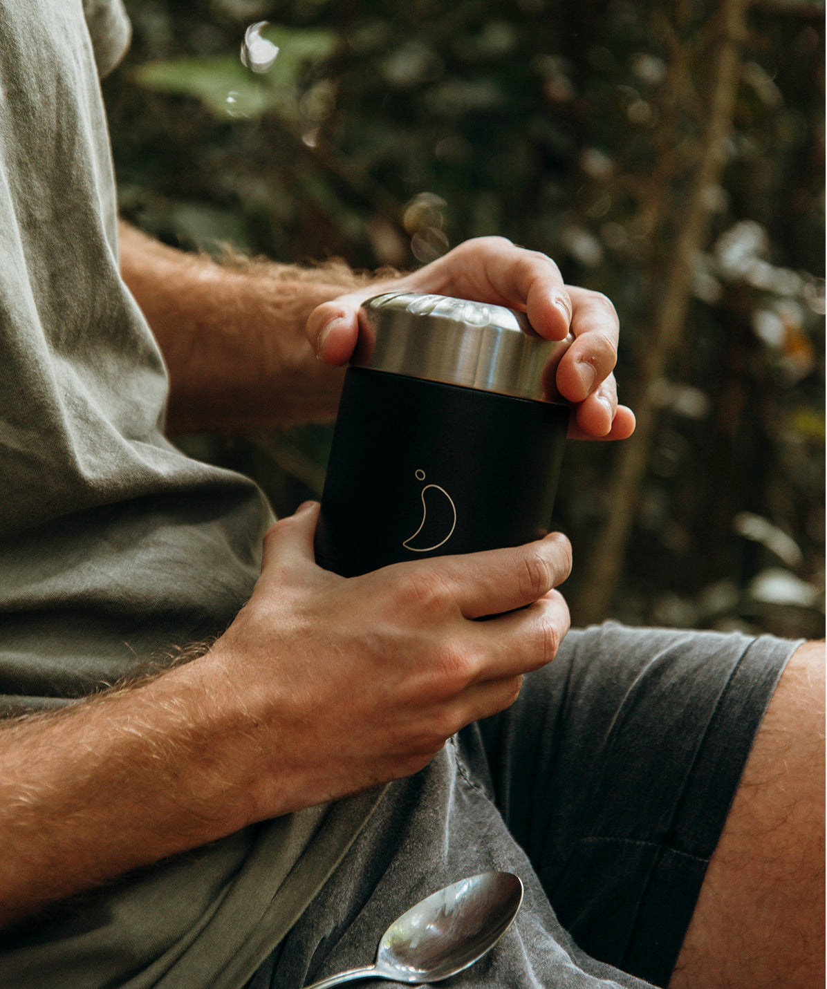 Manos sosteniendo y comiendo de un Termo de Sólidos Chilly's Mate Negro 300ml en el exterior. Termo de comida portátil para un estilo de vida activo.