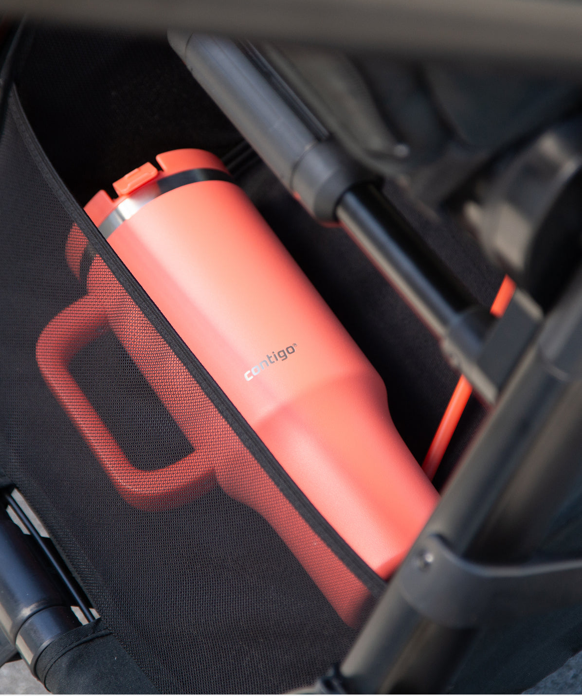 Termo Contigo Thermalock 1.2L coral en un portavasos de coche o carrito, ideal para mantenerse hidratado.