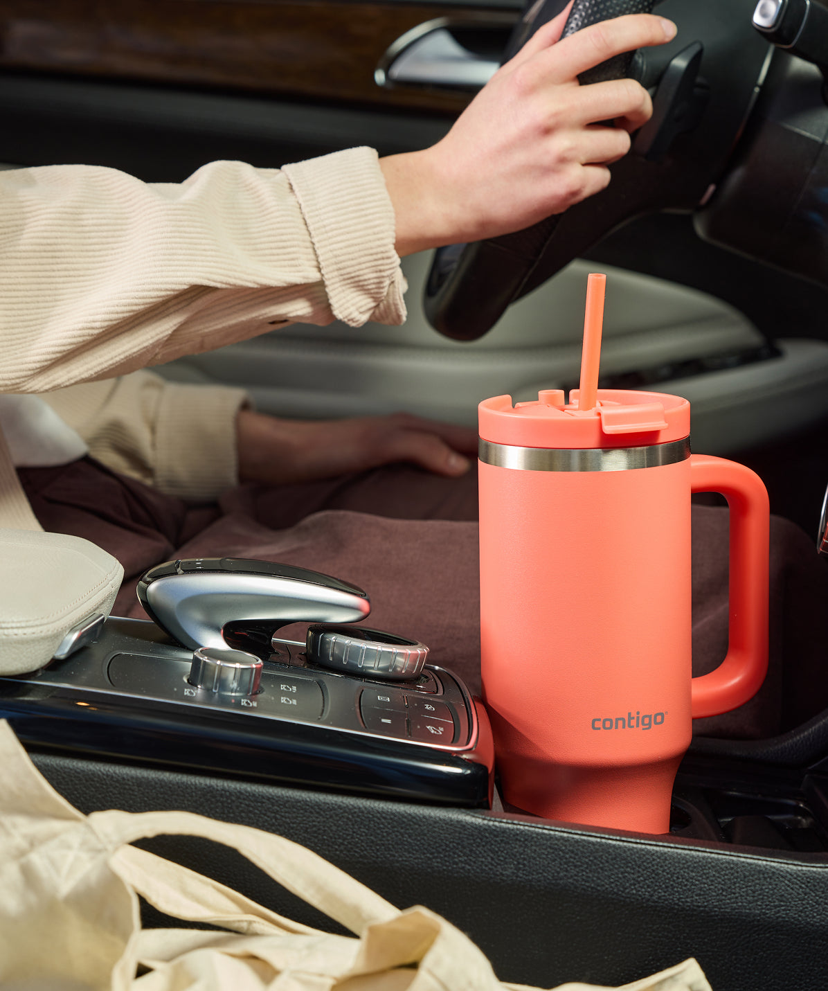 Termo Tumbler Contigo Thermalock 1.2L coral con asa, encajado en el portavasos del coche.