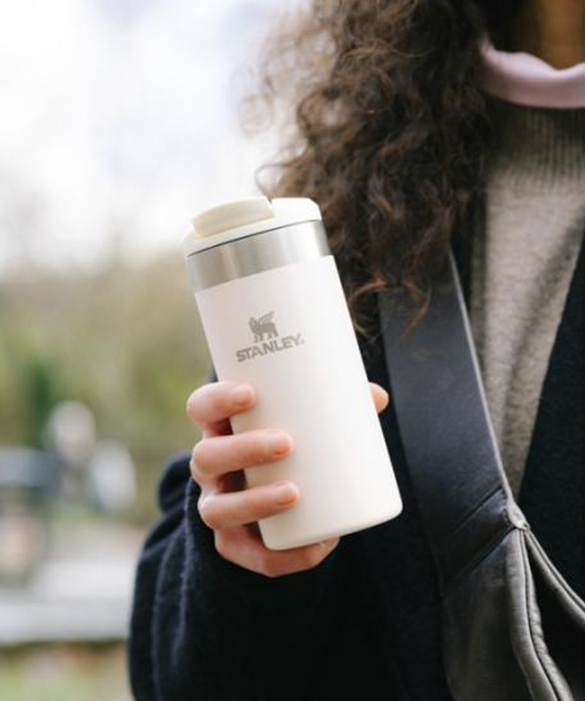 Persona en la calle con Vaso Stanley AeroLight™ Transit Mug Cream gloss 350ml en mano. Mantiene el café o té caliente en el camino.